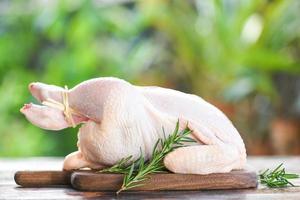 rosemary chicken meat - fresh raw chicken whole on wooden cutting board on nature green background photo
