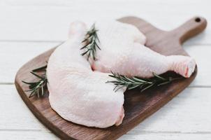 fresh raw chicken leg fillet on wooden cutting board background - chicken meat with rosemary photo