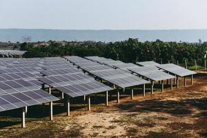 Solar panels in the solar farm with green tree and sun lighting reflect - solar cell energy or renewable energy concept photo