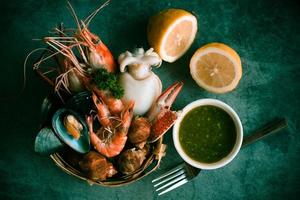 Steamer food served seafood buffet concept - Fresh shrimps prawns squid mussels  spotted babylon shellfish crab and seafood sauce lemon on plate black stone background photo