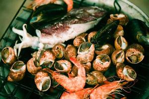 shellfish grilled seafood on stove - crab  prawns shrimps squid mussels cooked burn on grill barbecue holiday party on the beach photo