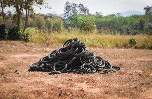 Old tires on the grass - industrial landfill for the processing of waste tires and rubber tyres pile of old tires and wheels for rubber recycling tyre dump photo