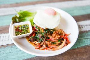 Rice topped with stir fried pork beef meat with holy basil and fried egg - Thai food spicy fried recipe with vegetables and chili sauce photo
