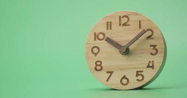 el reloj de madera que muestra la hora a las 10 am y 7 minutos sobre un fondo verde.
