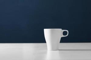 White cup on blue background. Blank ceramic cup photo