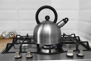 metal kettle on a gas stove. kettle boiling on a gas stove. Focus on a spout. Tea kettle with boiling water on gas stove photo