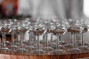 Many elegant empty glasses of wine or champagne on the wooden table in wedding day. Set of blank empty glasses displayed in rows. Preparation for the holiday