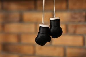 small decorative black boxing gloves. boxing gloves hang on nail on texture wall with copy space for text. Retirement concept.selective focus photo