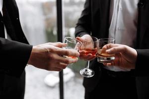 reunión de negocios. los hombres sostienen vasos de whisky. fiesta de hombres. mano con una bebida de alcohol foto