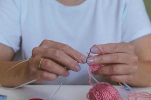 girl knits yarn with knitting needles and crochet at home. in a white t-shirt. hand knits photo