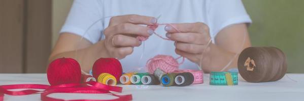 girl knits yarn with knitting needles and crochet at home. in a white t-shirt. hand knits photo