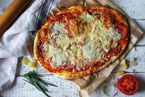 Traditional pizza Margarita prepared at home on a wooden table with a linen napkin. photo
