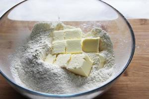Flour and butter cubes in a large glass bowl. Homemade cake. Housework. photo