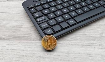 Golden Bitcoin next to a black computer keyboard. New technological economy concept. photo
