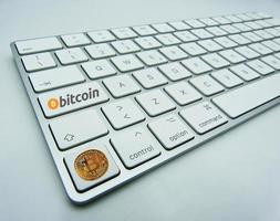 símbolo de bitcoin dorado en un botón de un teclado de computadora blanco. nuevo concepto de economía tecnológica. foto