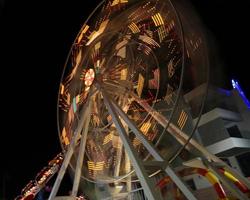 Round ferris wheel spins fast at black night photo