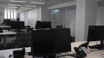 inquietante ufficio open space vuoto con file di più postazioni di lavoro durante il blocco. pan lento a sinistra video