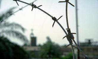 Old rusty security barbed wire fence on blue sky photo