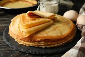 Concept of tasty breakfast with thin pancakes on wooden table photo