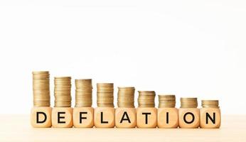 Deflation concept. Text on wooden blocks and stacked coins. Copy space photo