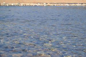 Colored pebbles under water at the coast Close-up. Stones under water. Background. photo