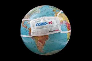 Surgical mask with Covid-19 written on planet Earth   Concept of global spread of Covid-19. Corona coronavirus outbreak photo