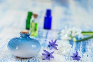 Composición con aceite esencial y flor de jacinto en botella de vidrio y botella de cerámica sobre fondo de madera vieja foto