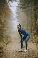 Young woman take a break during outdoor exercise on the forest trail at autumn photo