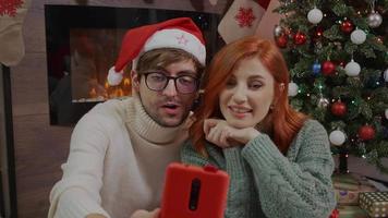 Happy couple celebrating Christmas with their friends using a video call.