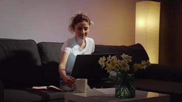 dolblij vrouw zittend op de bank thuis op laptop scherm lachend. video