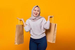 Portrait of surprised asian woman holding shopping bag over yellow background photo