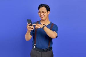 Smiling man using mobile phone to browse with empty space over purple background photo