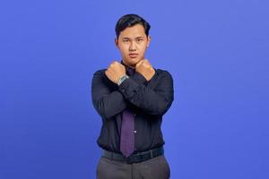 Serious young handsome businessman crossed hand and showing refusal gesture on purple background photo