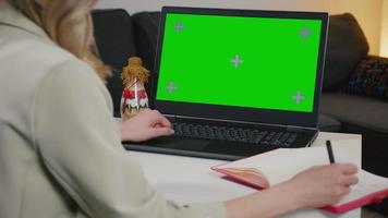 Business woman at home working on a laptop with green screen display. video