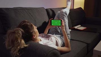 kvinna som stannar hemma och tittar på telefonens gröna skärm. video