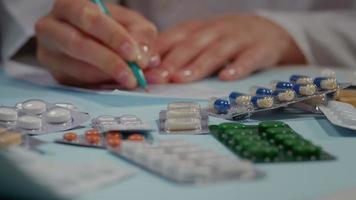 Pills on the table, doctor hands writing a prescription in a medical. video