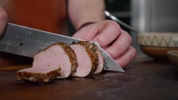 le chef coupe un steak de porc juteux sur une planche à découper rustique sur fond de bois.