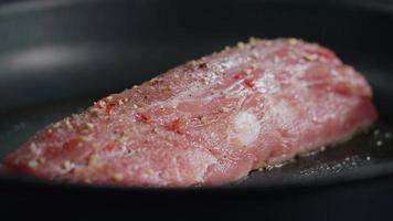 Cerrar la carne de cerdo cruda sazonada se fríe en una sartén caliente. video