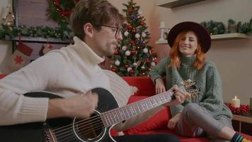 Couple having fun and singing on decorated cozy living on christmas season.