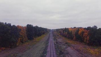 sobrevolar una vía férrea con un tren perdido, sobrevolar rieles dentro de un bosque, vuelo aéreo en tren desde una altura, buscando una carretera con drones. video