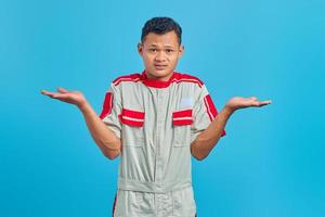 Shocked asian mechanic portrait with confused and displeased expression on yellow background photo