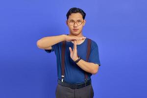 Man wearing blue shirt and glasses showing timeout gesture on purple background photo