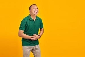 Attractive asian young man laughing out loud at funny on yellow background photo