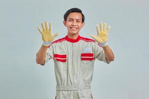 Portrait of cheerful handsome man wearing mechanical uniform showing palms over gray background photo