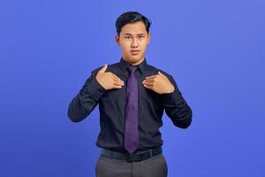 Confundido joven asiático apuntando a sí misma sobre fondo púrpura foto