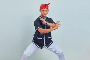 Foto de joven deportista vestido con kimono practicando karate aislado sobre fondo gris. mirando a la camara