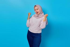 Portrait of excited asian woman celebrating success with raised arms photo