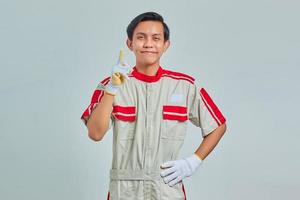 Portrait of excited handsome man wearing mechanical uniform having creative idea and looking at camera over gray background photo