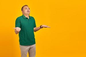 Portrait of asian man surprised with confused and displeased expression on yellow background photo