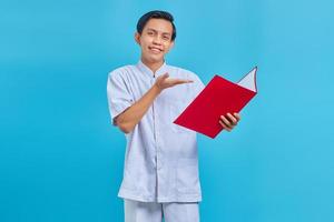 Portrait of smiling male nurse pointing at folder with palms over blue background photo